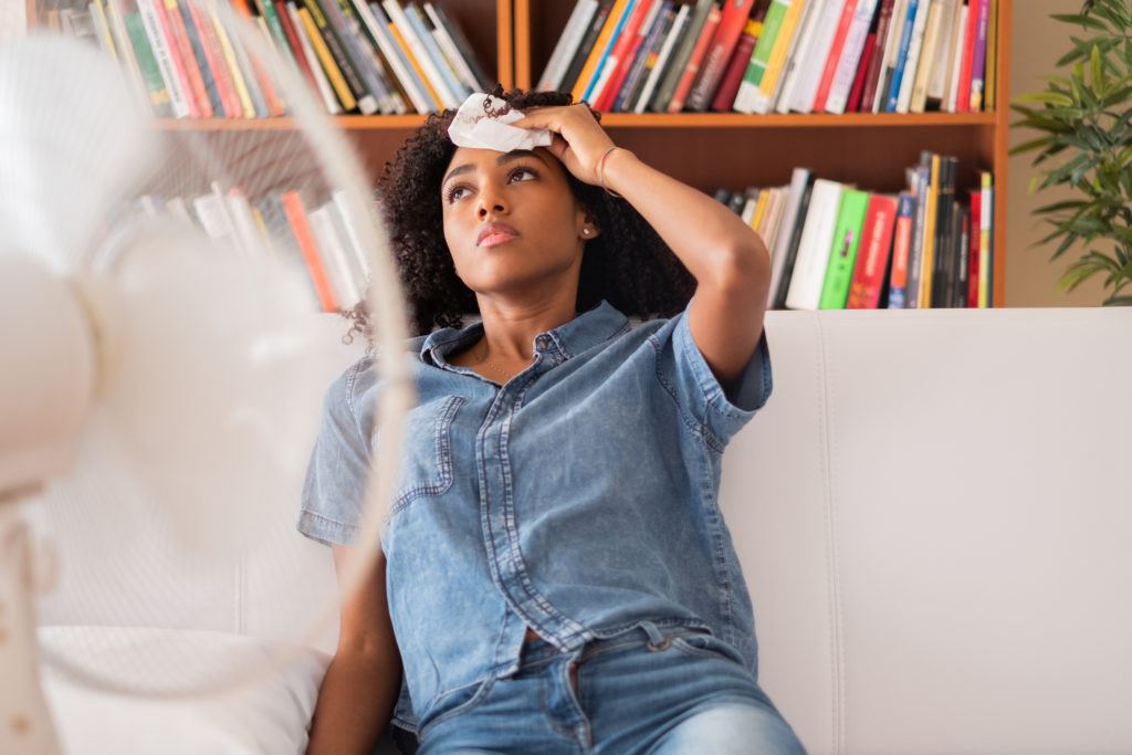 Woman sweating and trying to refresh at home