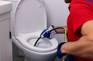 Plumber unclogging blocked toilet with hydro jetting